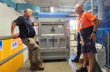 Two men talking in front of Mil-tek E319 baler ready for installation