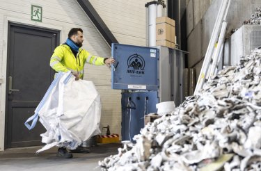 man putting empty big bag into baler