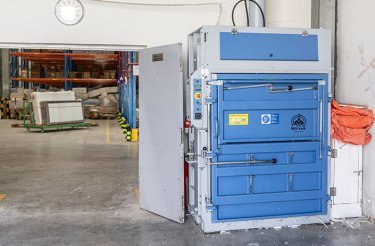 hydraulic baler against wall next to door opening